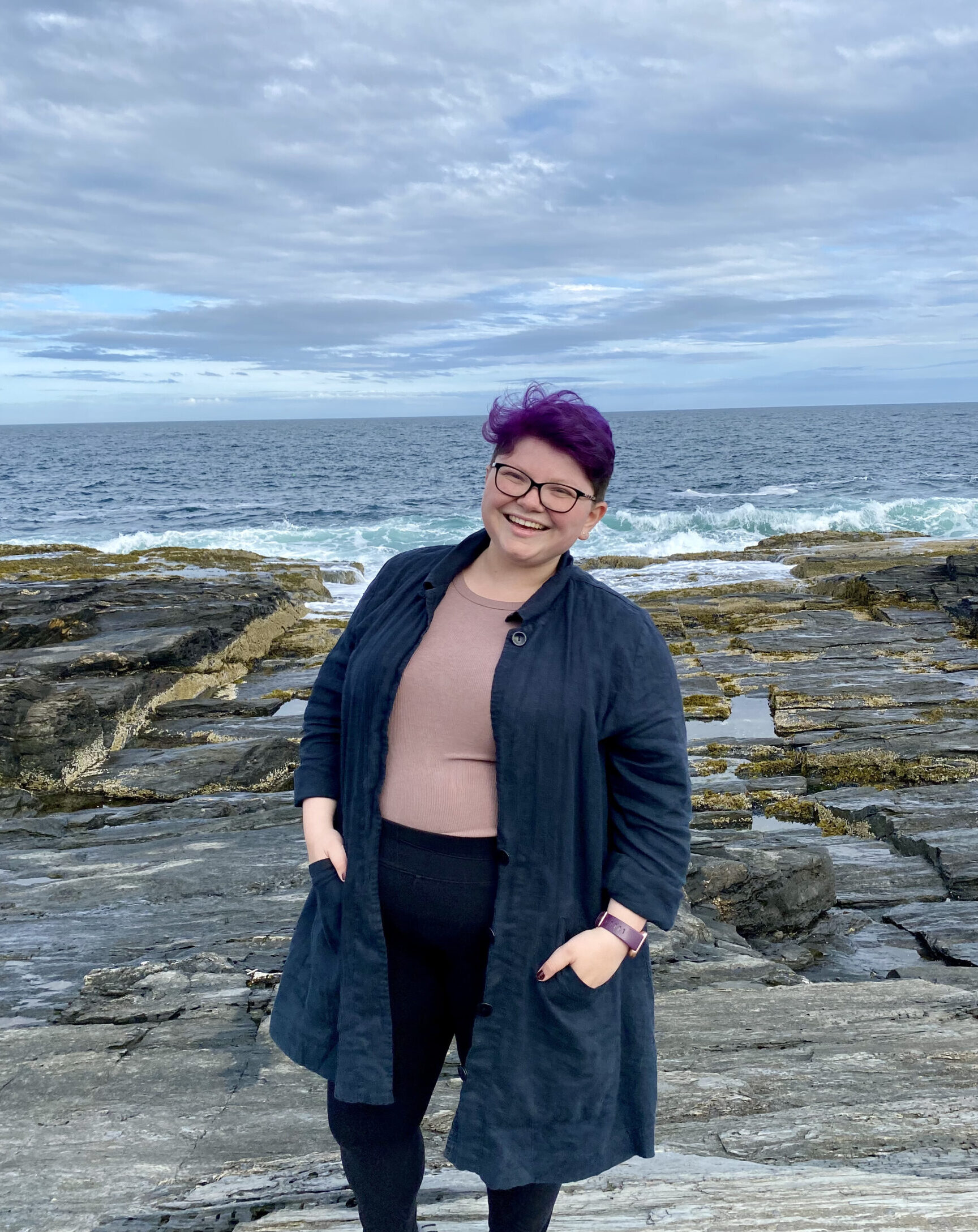 Sophia (the new TerraCorps member) at Cape Elizabeth, in a black cardigan sweater, purple shirt, and black pants. Her hair is also purple.