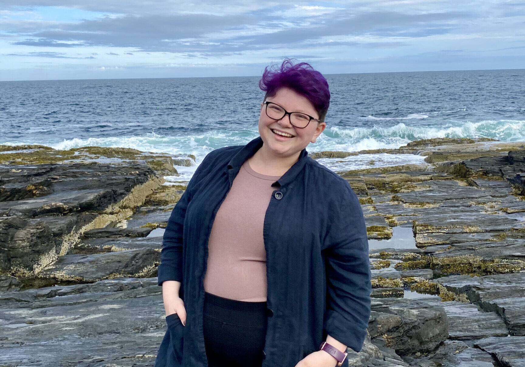 Sophia (the new TerraCorps member) at Cape Elizabeth, in a black cardigan sweater, purple shirt, and black pants. Her hair is also purple.